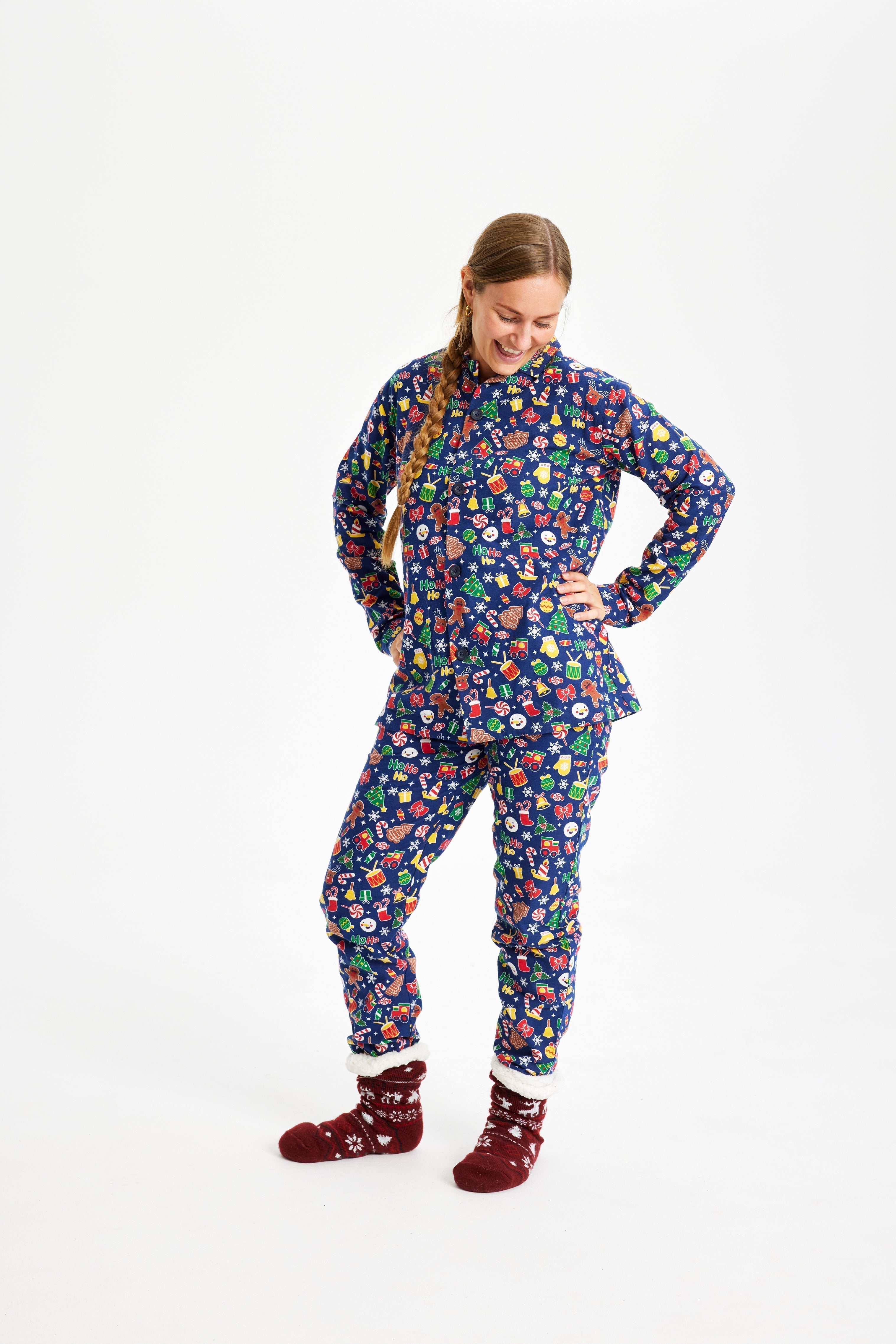 Une femme, les mains le long du corps, portant un pyjama de Noël bleu avec un imprimé de Noël.