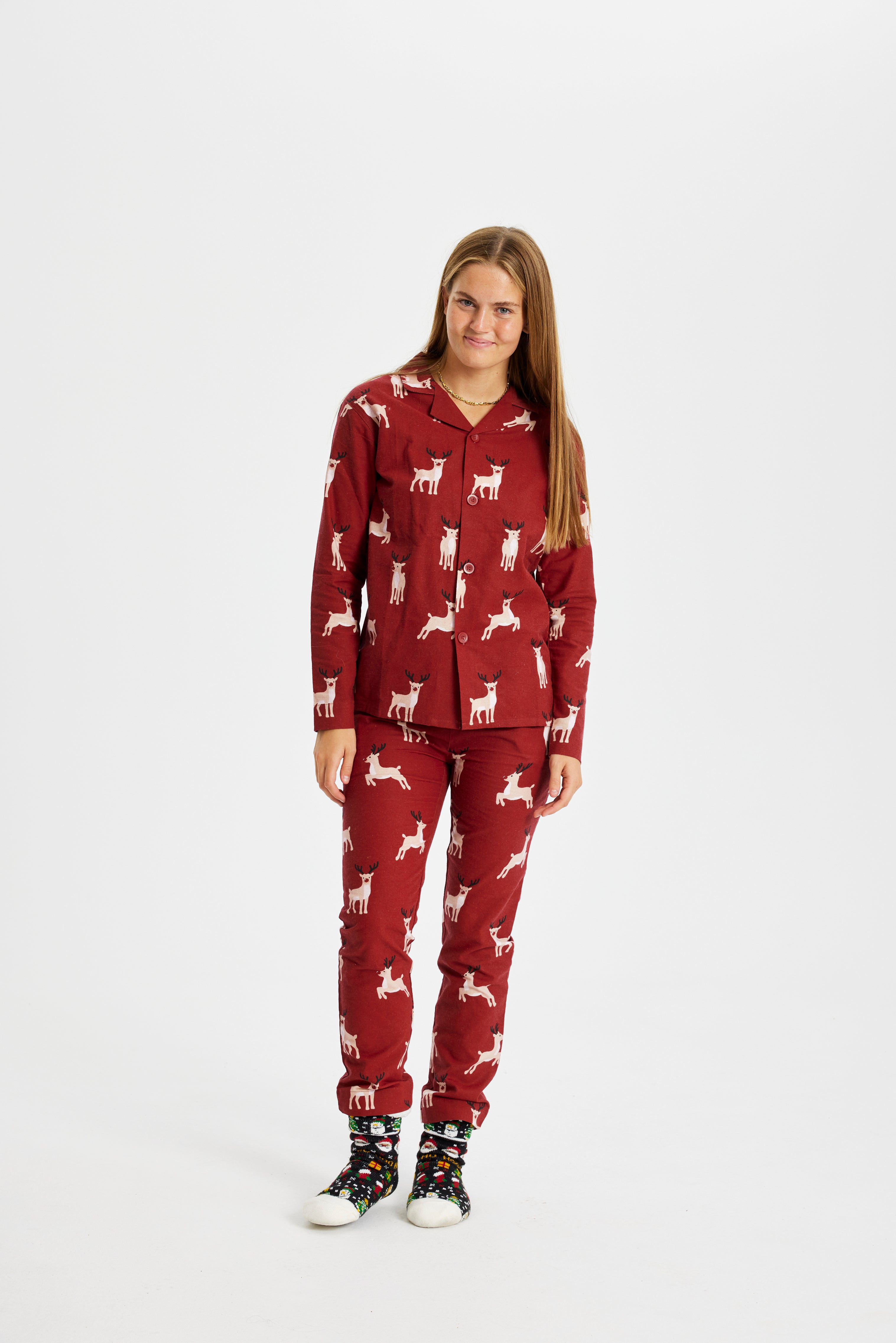 Une femme qui pose, portant un pyjama de Noël rouge foncé avec des rennes.