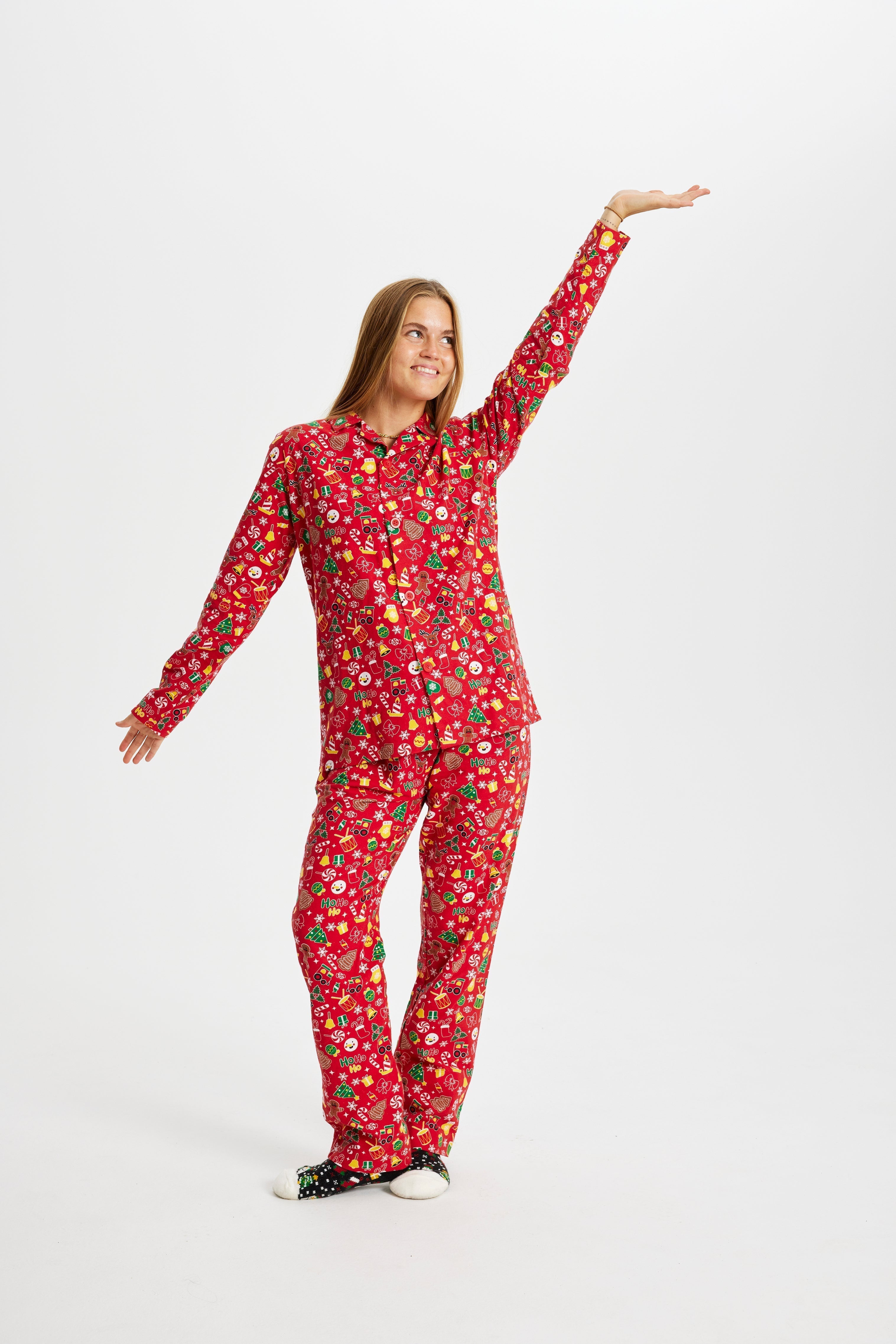 Une femme posant avec un pyjama de Noël rouge avec un imprimé de Noël.