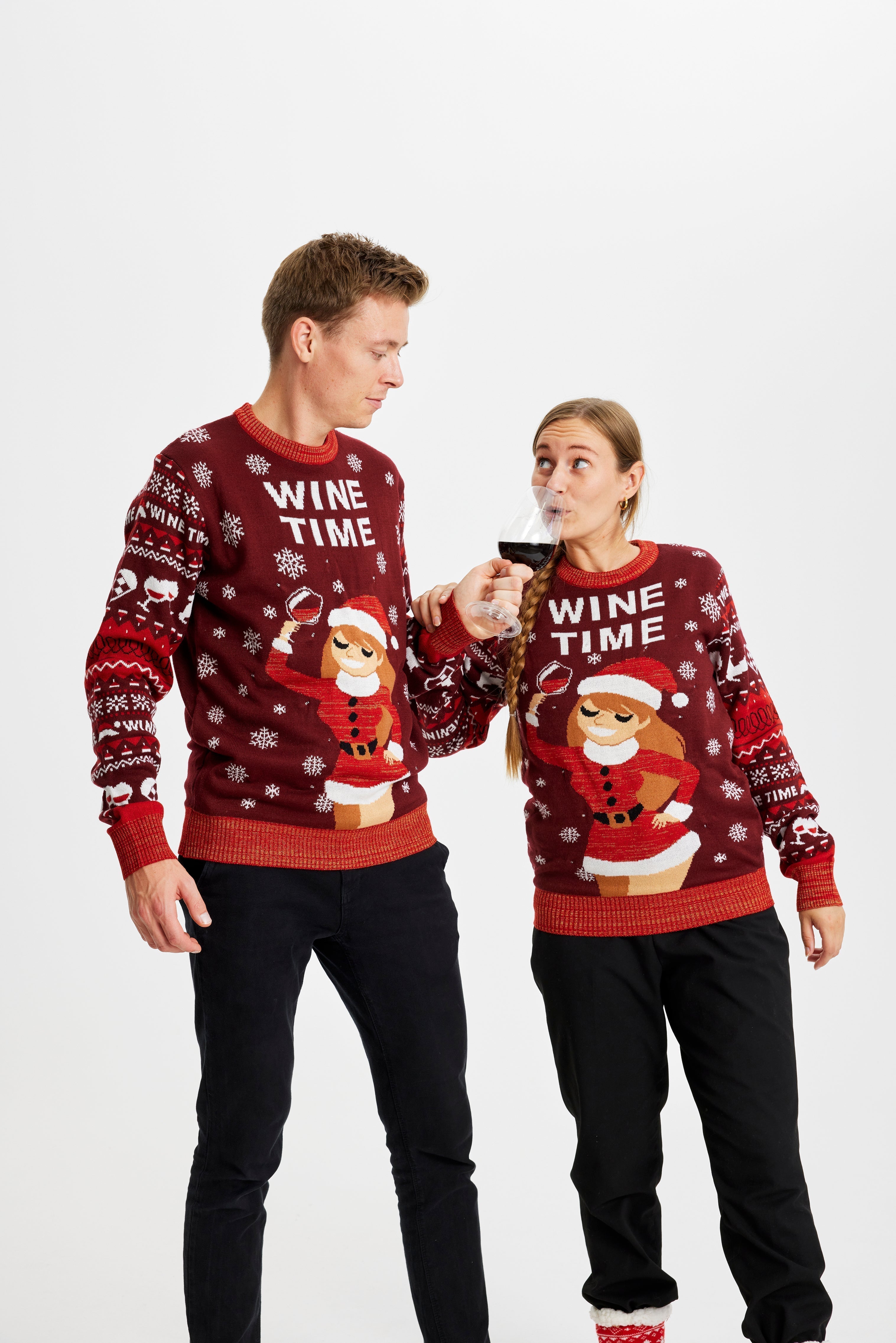 Un couple posant avec un pull de Noël rouge avec la citation 