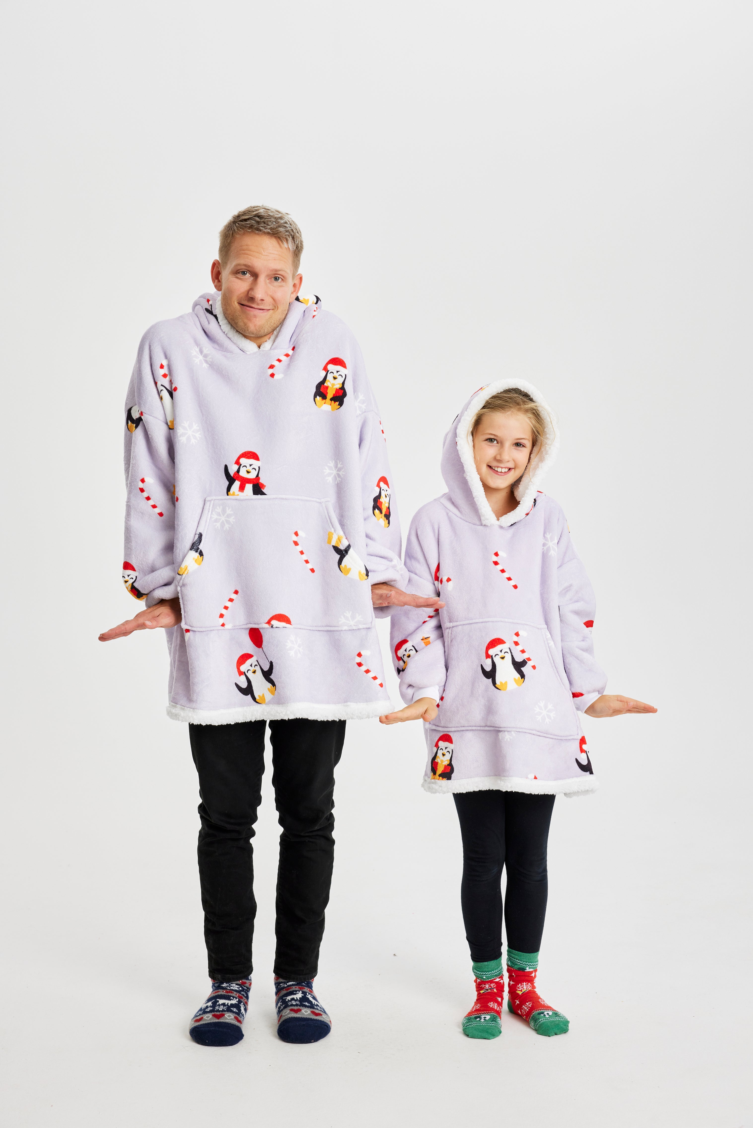 Un enfant et un homme portant un sweat à capuche de Noël violet clair avec des pingouins.