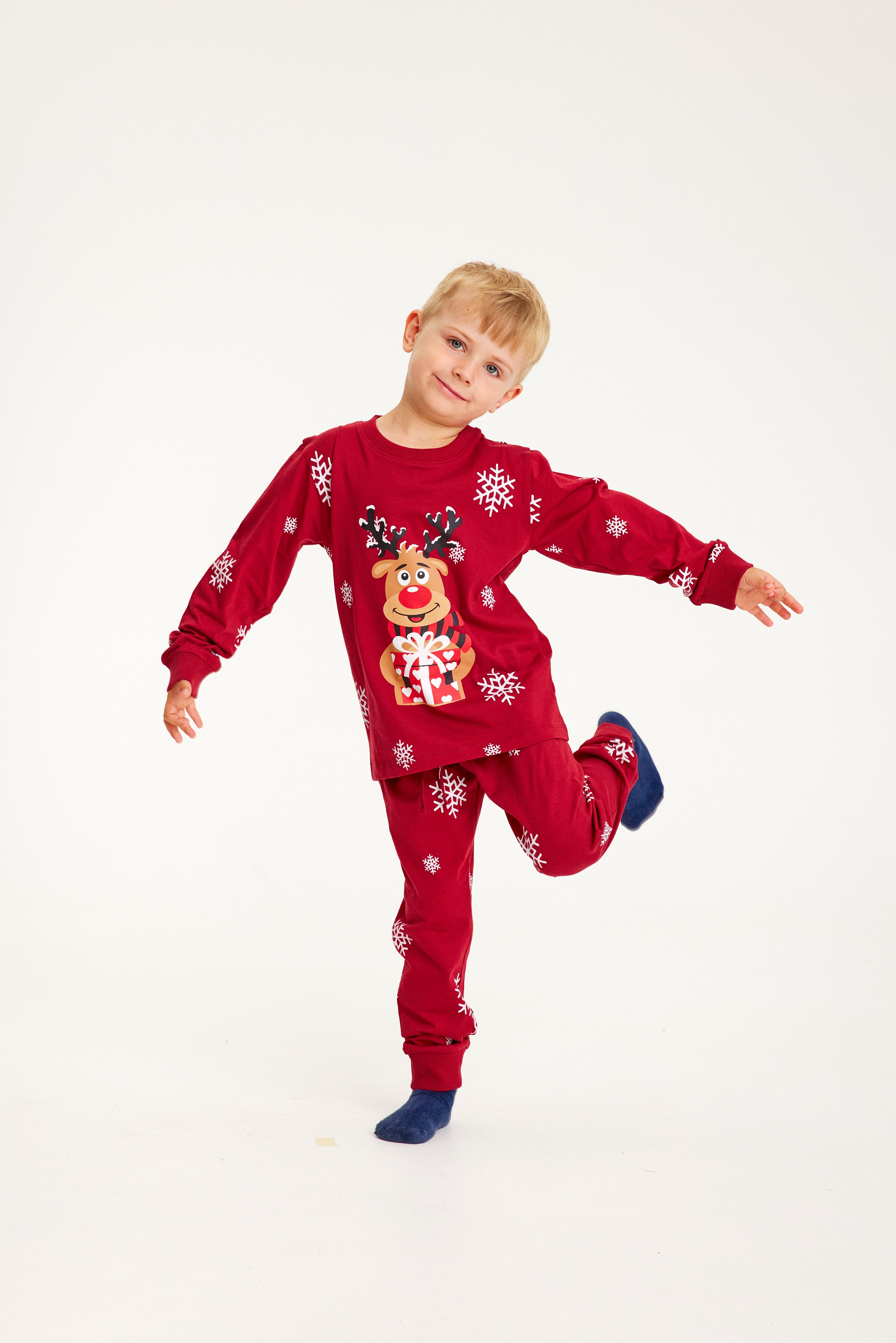 Et poserende barn iført røde julepyjamas med snefnug på.