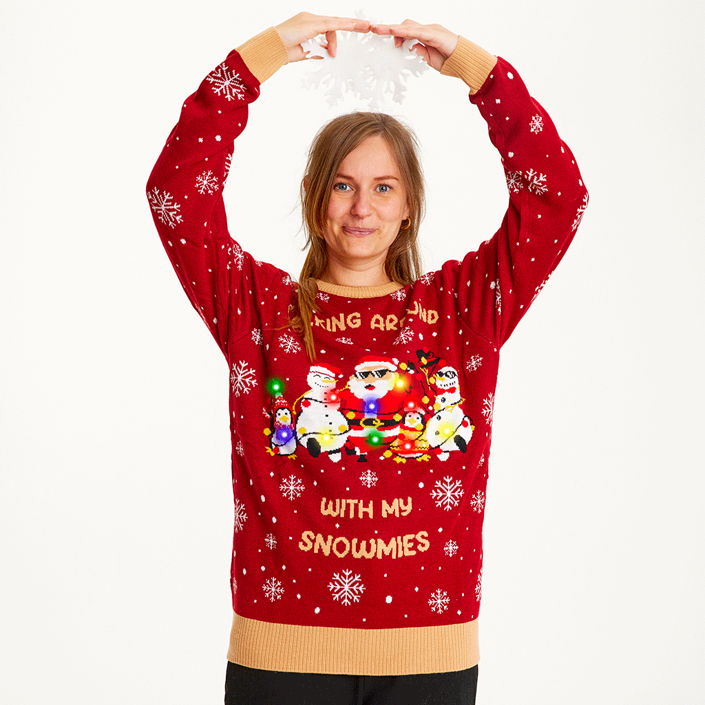Une femme pose vêtue d'un pull de Noël rouge avec la citation 